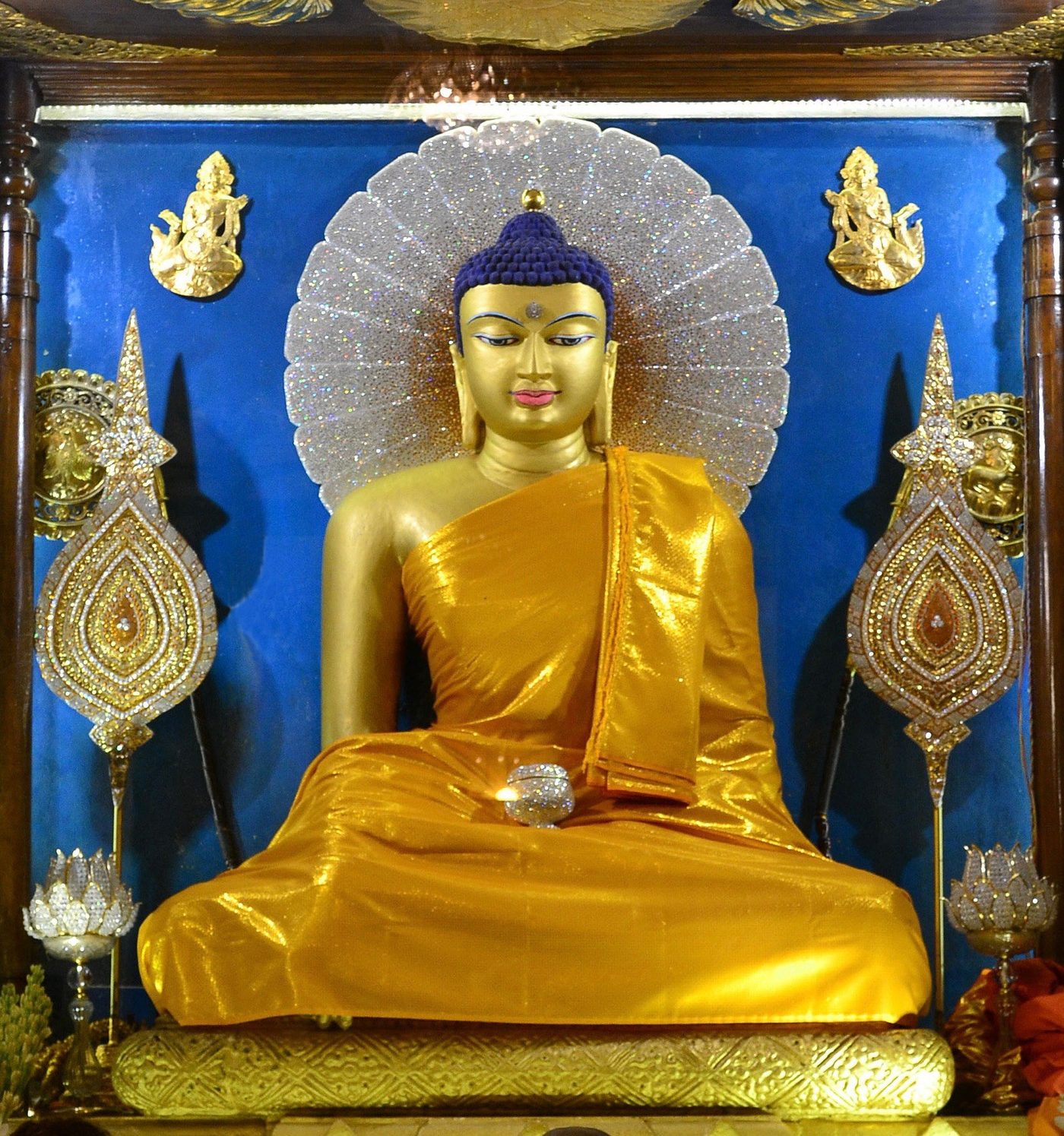 A golden Buddha statue at a shrine, surrounded by offerings
